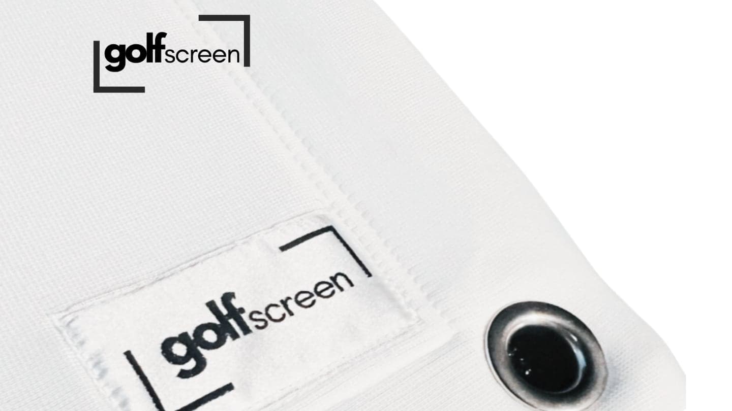 Close view of a finished impact screen edge: a metal eyelet set through the folded and twin-stitched hem, with the woven cloth visible around it